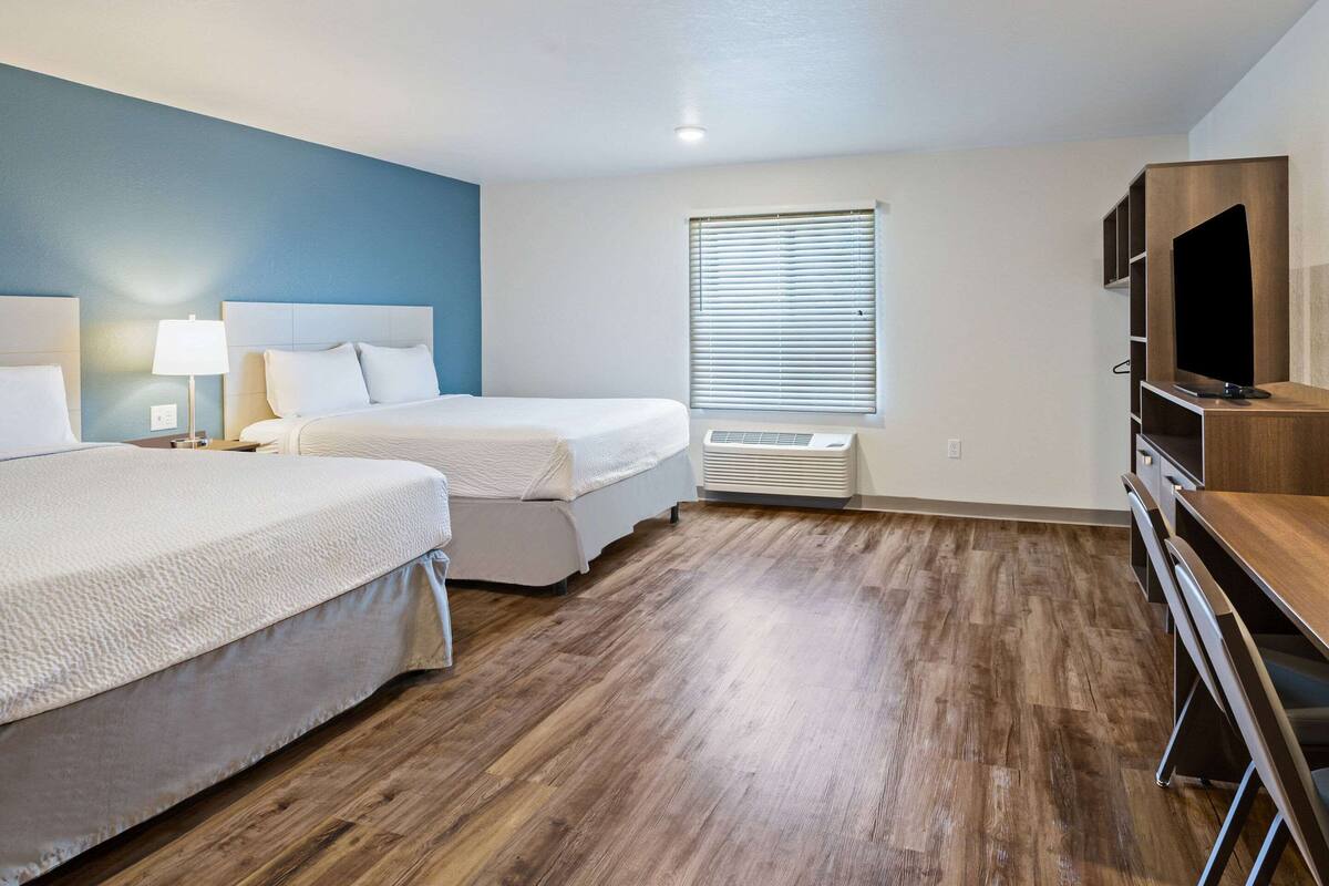 Habitación de hotel con dos camas, un televisor y piso de madera.