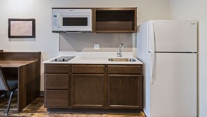 Cocina compacta con microondas, lavamanos y refrigerador.