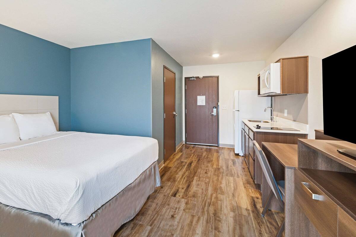 Una habitación de hotel con una cama, un kitchenette y una puerta que da a otra habitación.