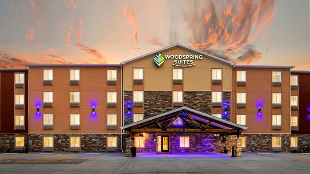 Un hotel con fachada de piedra, varias ventanas y un cartel que dice "Woodspring Suites".