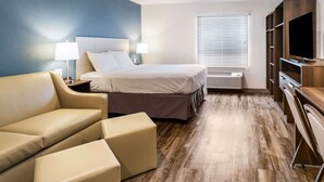 Una habitación de hotel con cama, sofá, televisión y escritorio.