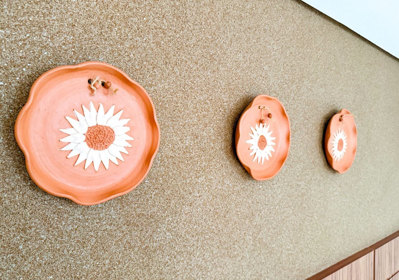 A textured surface with three ceramic plates with sun designs.