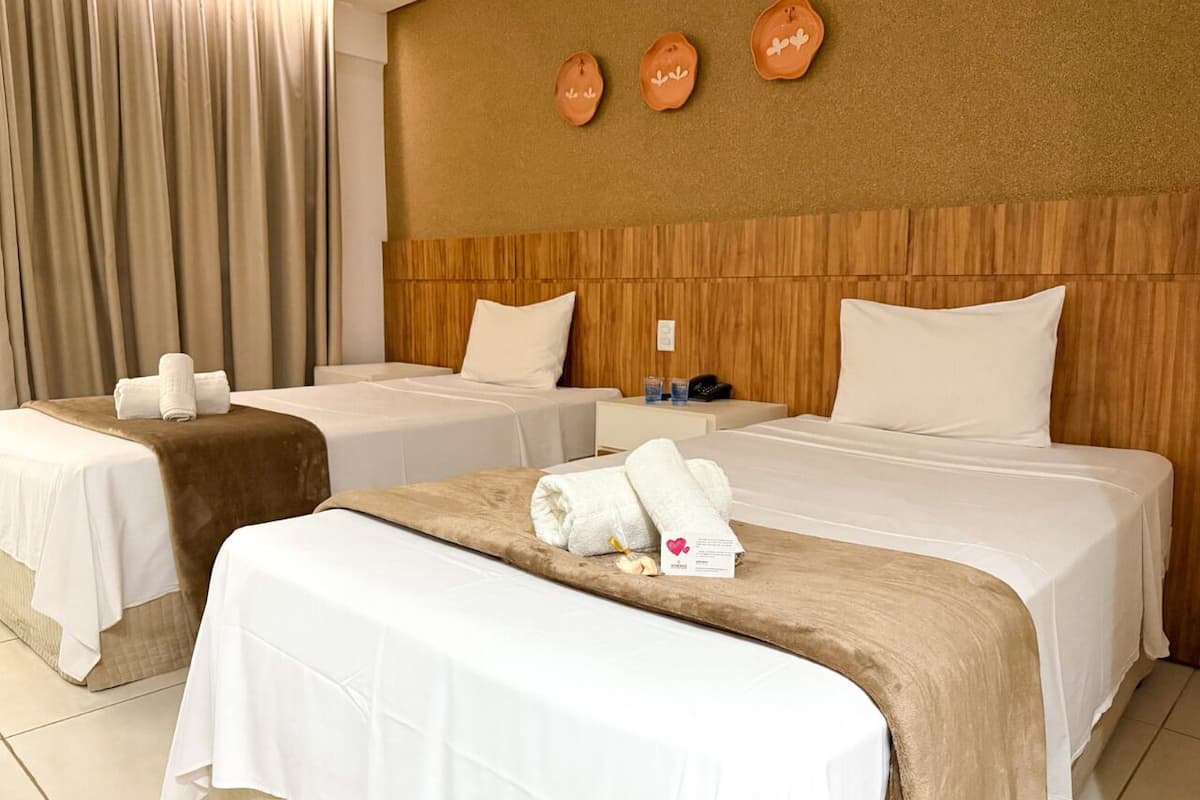 Een hotelkamer met twee bedden, een houten hoofdeinde, een wandklok en een handdoek op het bed.