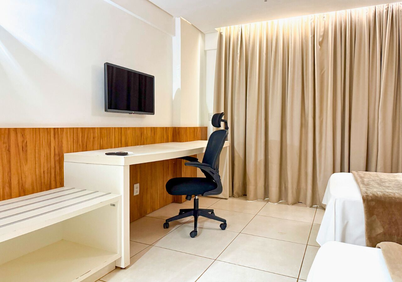 Une chambre d’hôtel équipée d’un bureau, d’une chaise, d’une télévision et d’un lit.