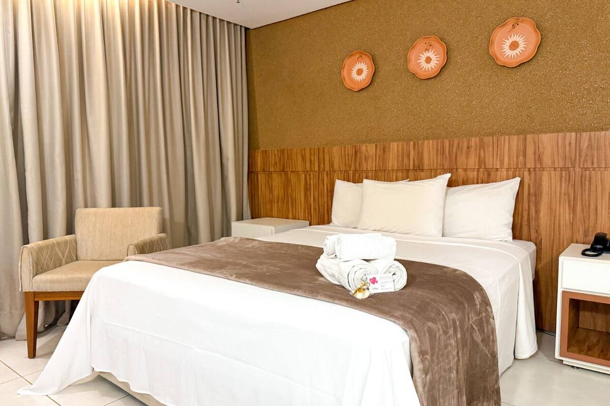 Een hotelkamer met een bed, een stoel en een nachtkastje.