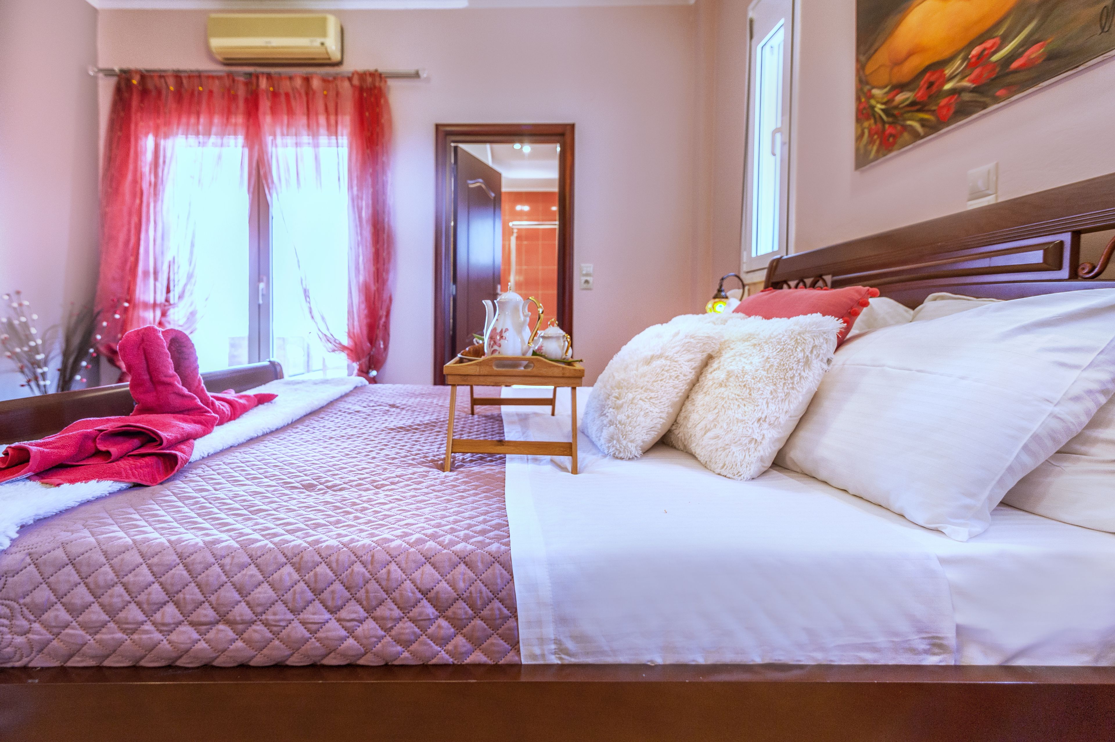 Une chambre d’hôtel avec deux lits, une tête de lit en bois, une table de chevet avec une lampe et une fenêtre avec des rideaux rouges.