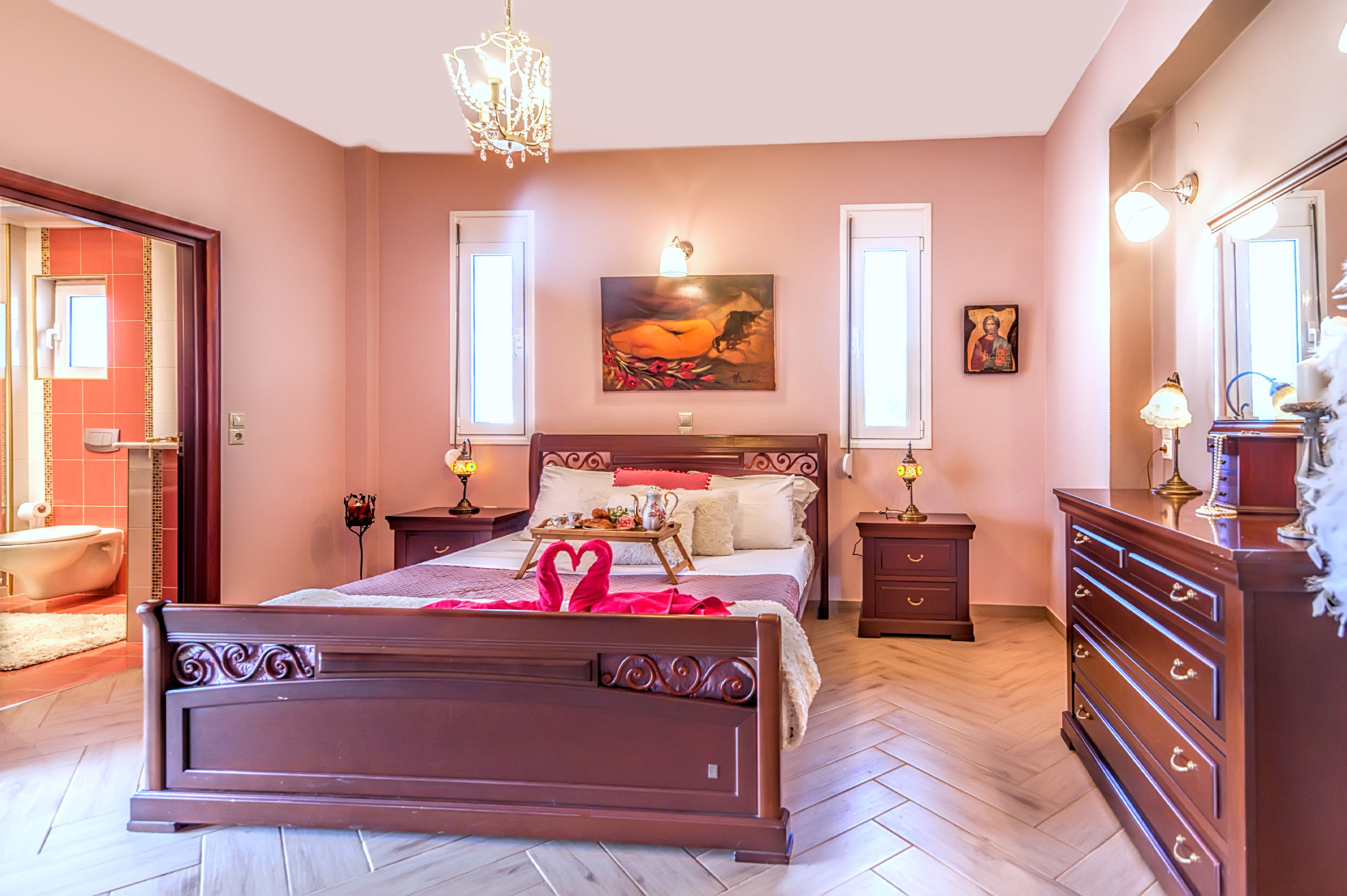 Una camera da letto con un letto grande, comodini, una cassettiera e un lampadario.