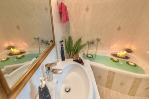 Un baño lujoso con una bañera grande, un lavamanos separado y un espejo.