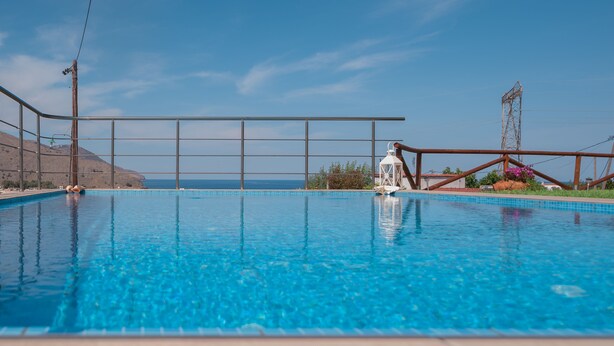 Ein klares, blaues Schwimmbecken mit Blick auf den Ozean und die Hügel.