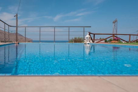 Una piscina al aire libre, sombrillas, sillones reclinables de piscina