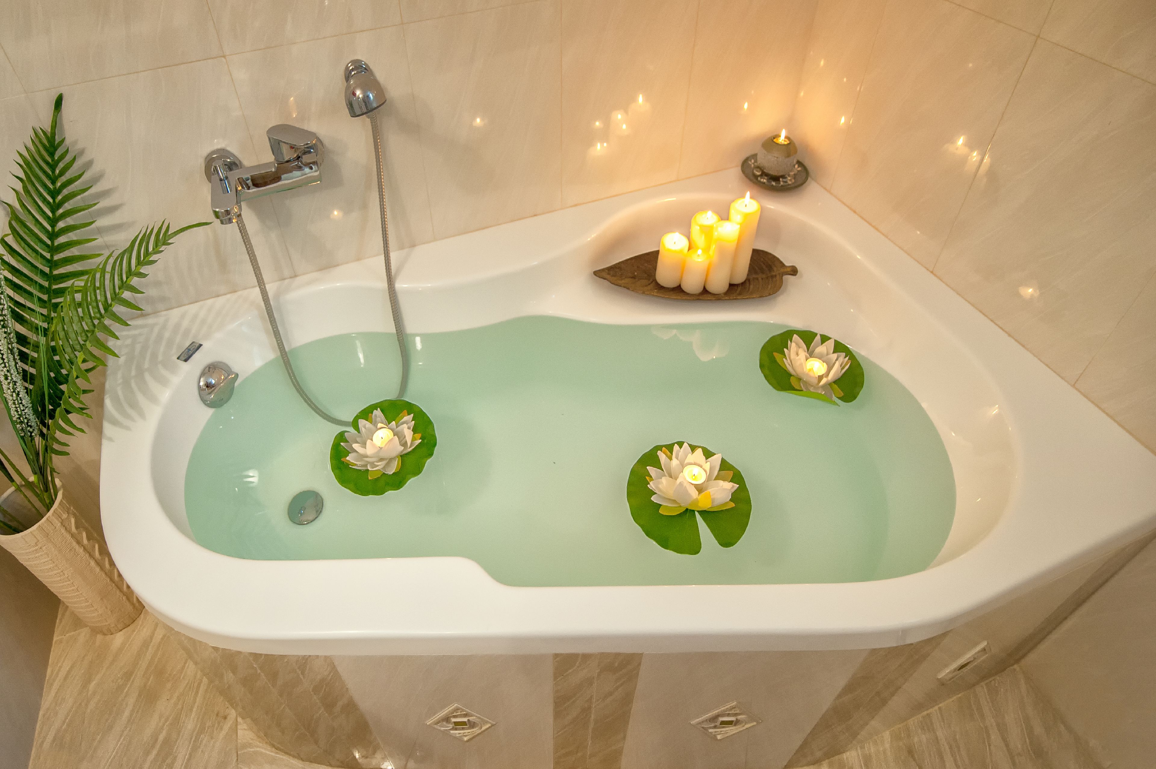 Une baignoire décorée de nénuphars et de bougies.