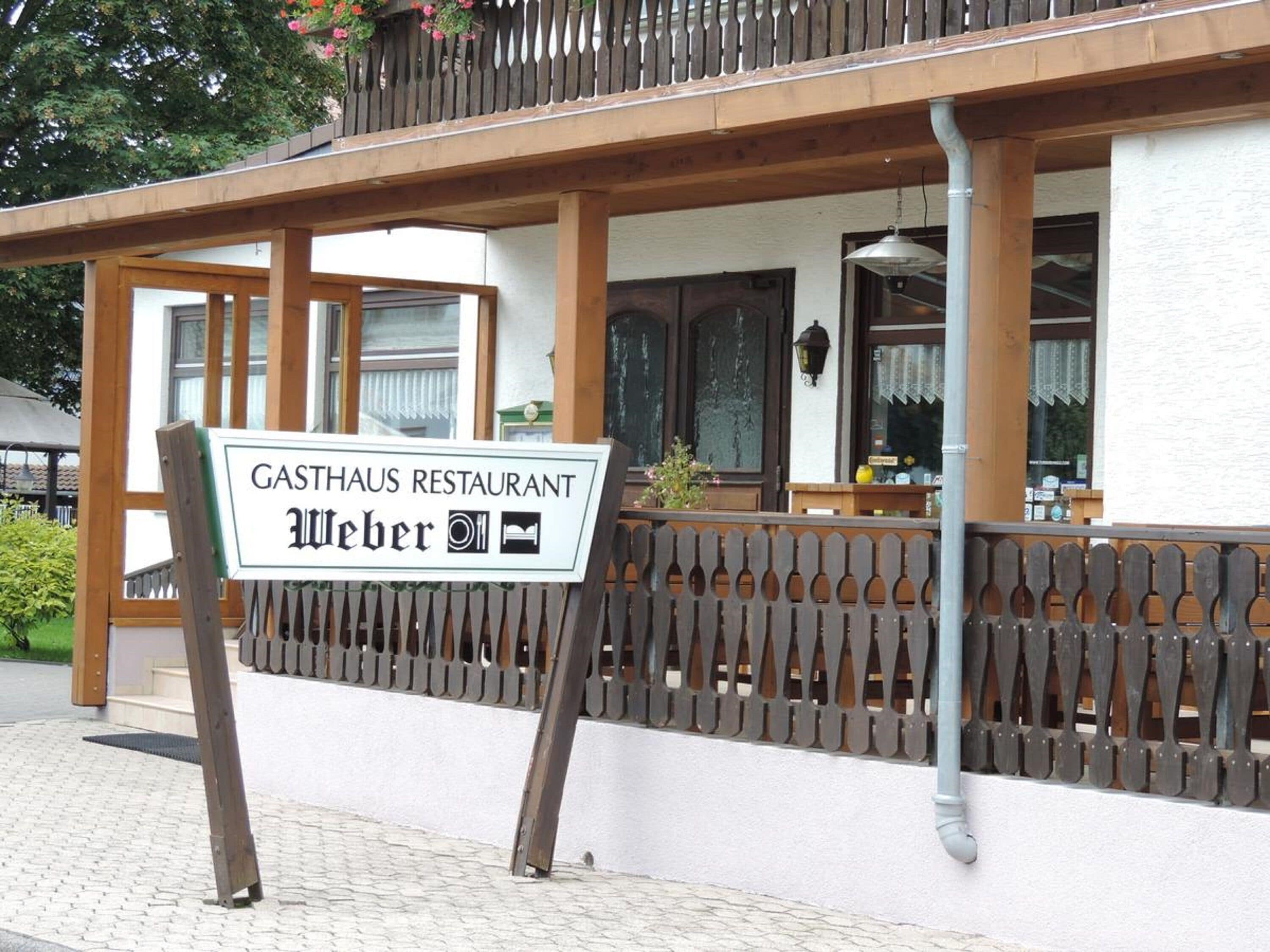 A restaurant named "GASTHAUS RESTAURANT Weber" with a wooden balcony and a white exterior wall.