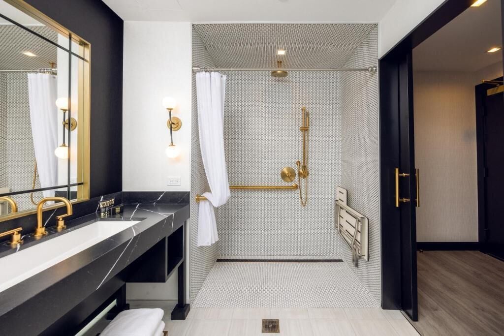 A modern bathroom with a large mirror, dual sinks, a shower with a glass door, and a towel rack.