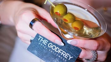 A person holding a martini glass with olives and a keychain labeled "THE GODFREY HOTELWOOD".