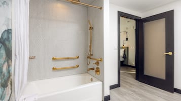 Un baño moderno con una bañera independiente, detalles en dorado y una zona de ducha con mampara de vidrio.