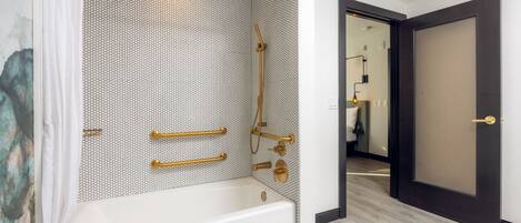 Un baño moderno con una bañera independiente, detalles en dorado y una zona de ducha con mampara de vidrio.