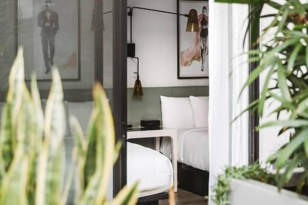 Ein modernes Schlafzimmer mit großem Fenster, einem Bett, einem Schreibtisch und einem Sessel.