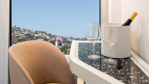 A chair and a table with a wine glass and a bottle of wine, overlooking a cityscape.