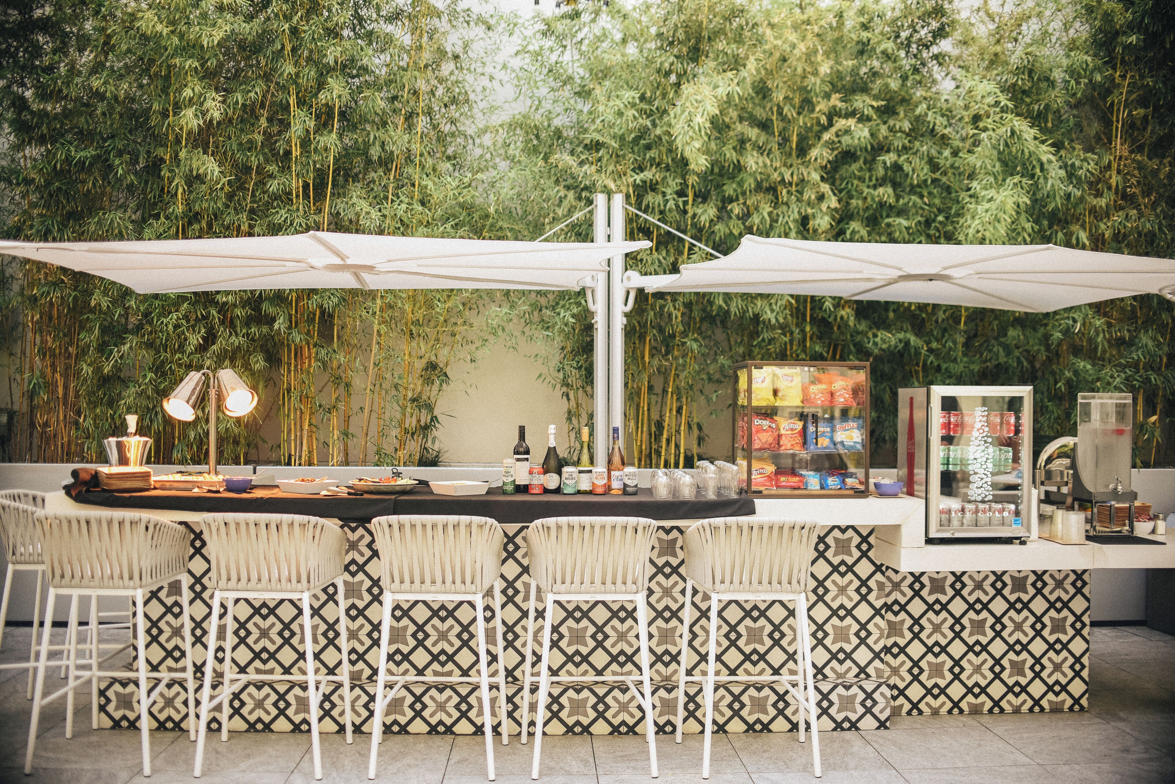 An outdoor bar area with a counter, bar stools, and a large umbrella.