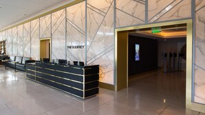 A reception area with a marble wall design, a reception desk, and a digital screen displaying a cityscape.