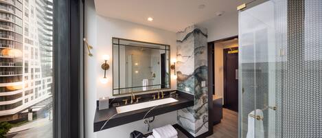 A modern bathroom with a large mirror, dual sinks, and a glass shower enclosure.