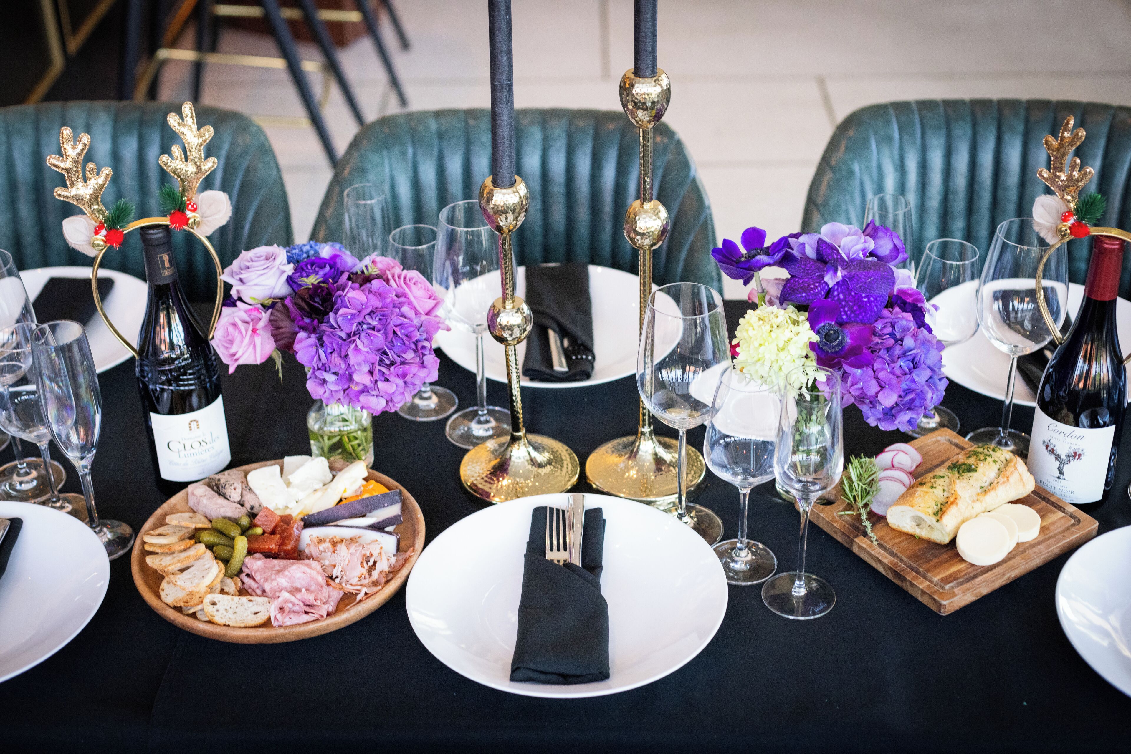 A formal dining table set with plates, cutlery, glasses, and wine bottles.