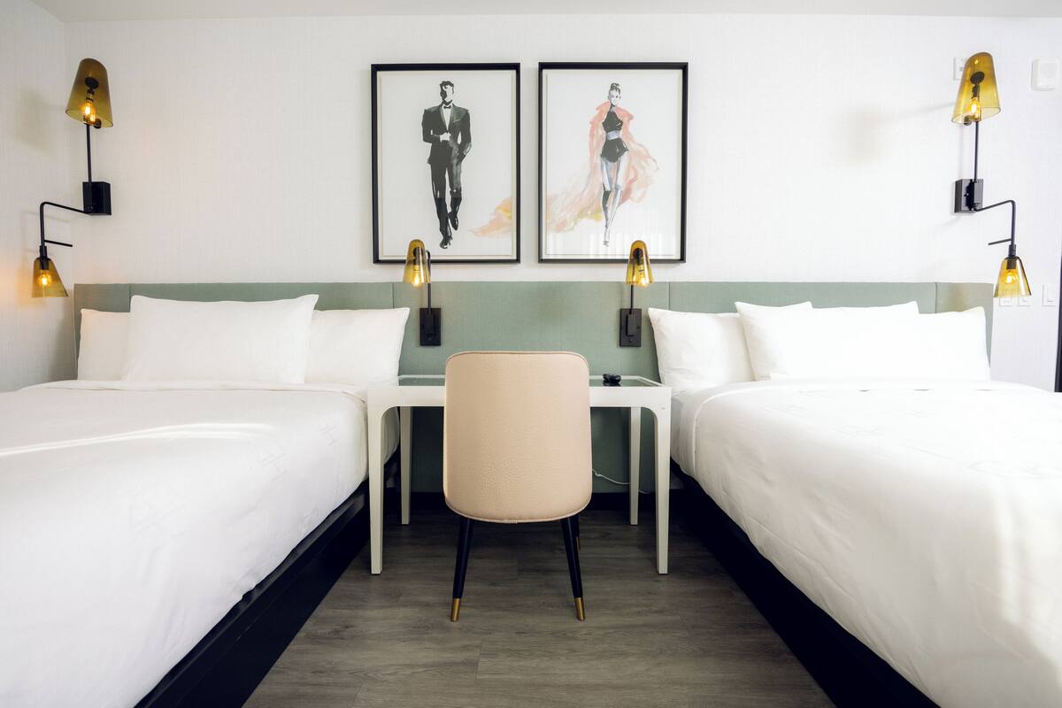 Ein Hotelzimmer mit zwei Betten, einem Sessel und zwei Wandlampen.