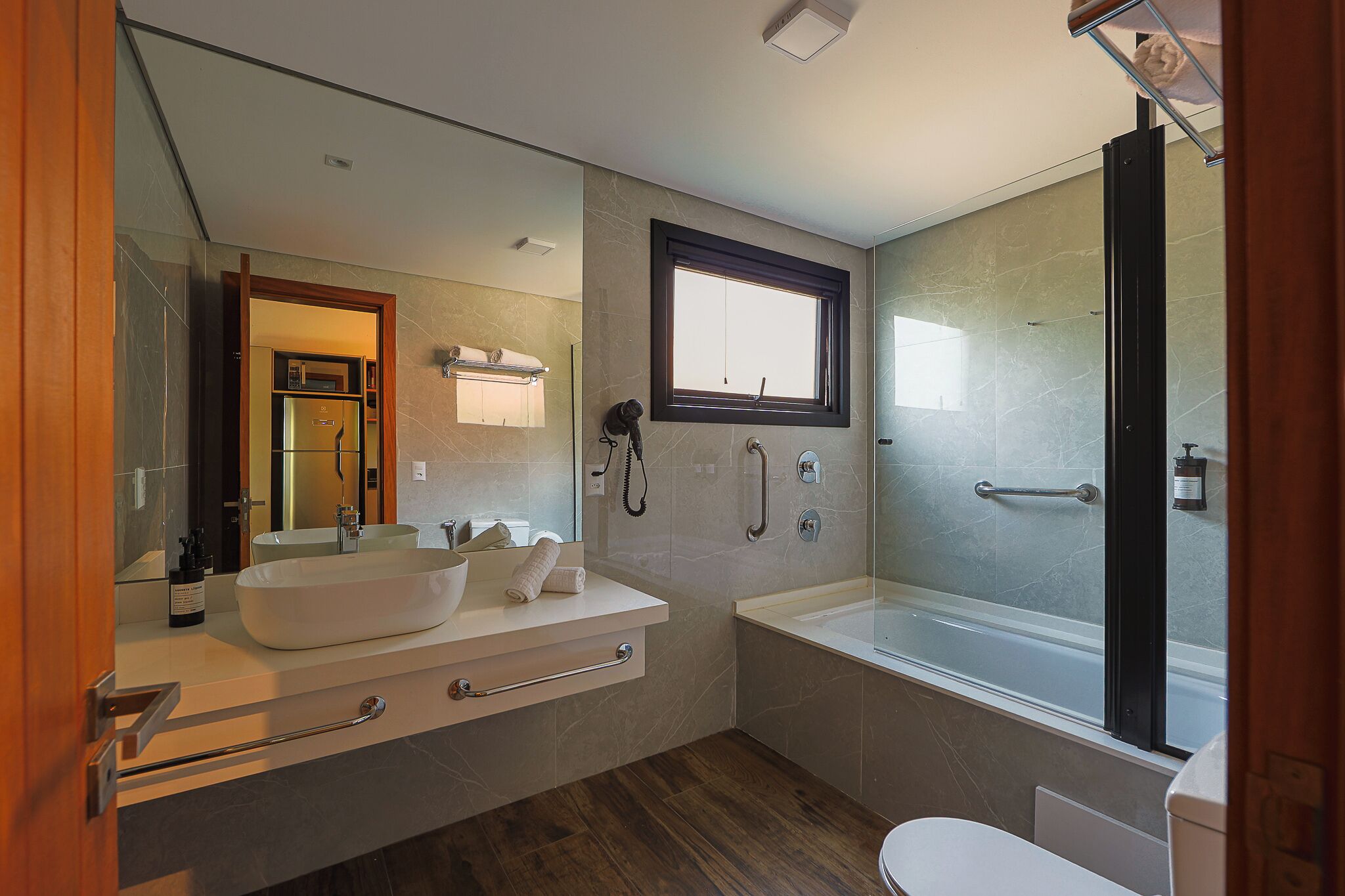 A modern bathroom with a large bathtub, a walk-in shower, and a vanity with a large mirror.