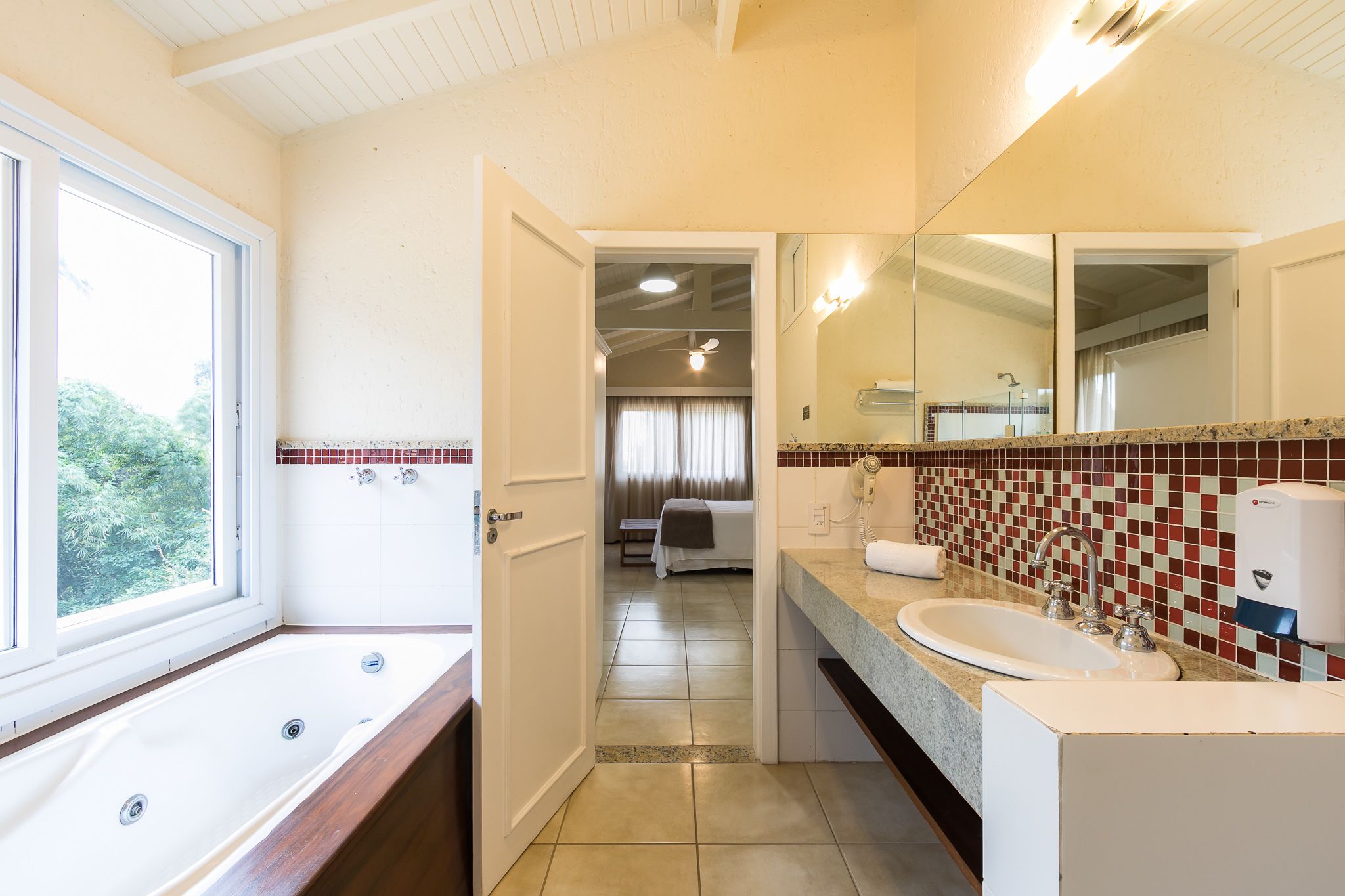 A bathroom with a bathtub, a sink, and a mirror.