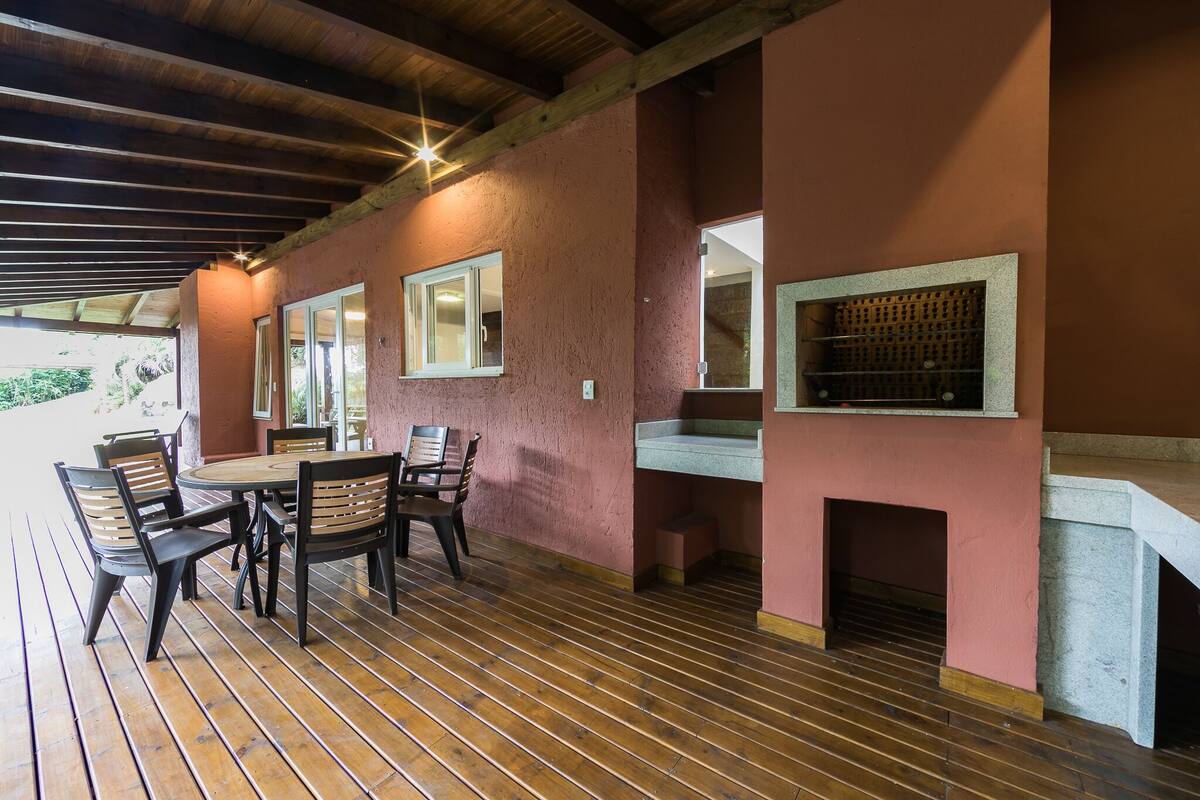 An outdoor patio with a wooden table and chairs, a stone fireplace, and a wine rack.