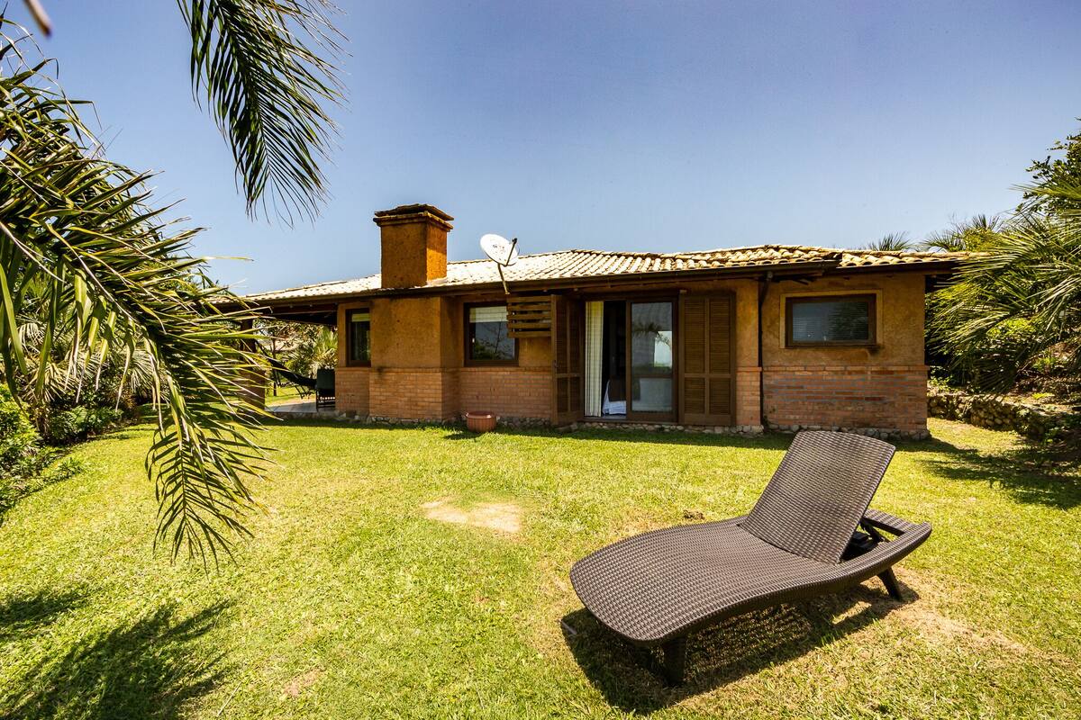 A single-story house with a brick exterior, a tiled roof, and a small patio area with a single lounge chair.