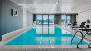 An indoor swimming pool with clear views of mountains, lounge chairs, and a modern design. - Quadrum Ski & Yoga Resort (Kazbegi)