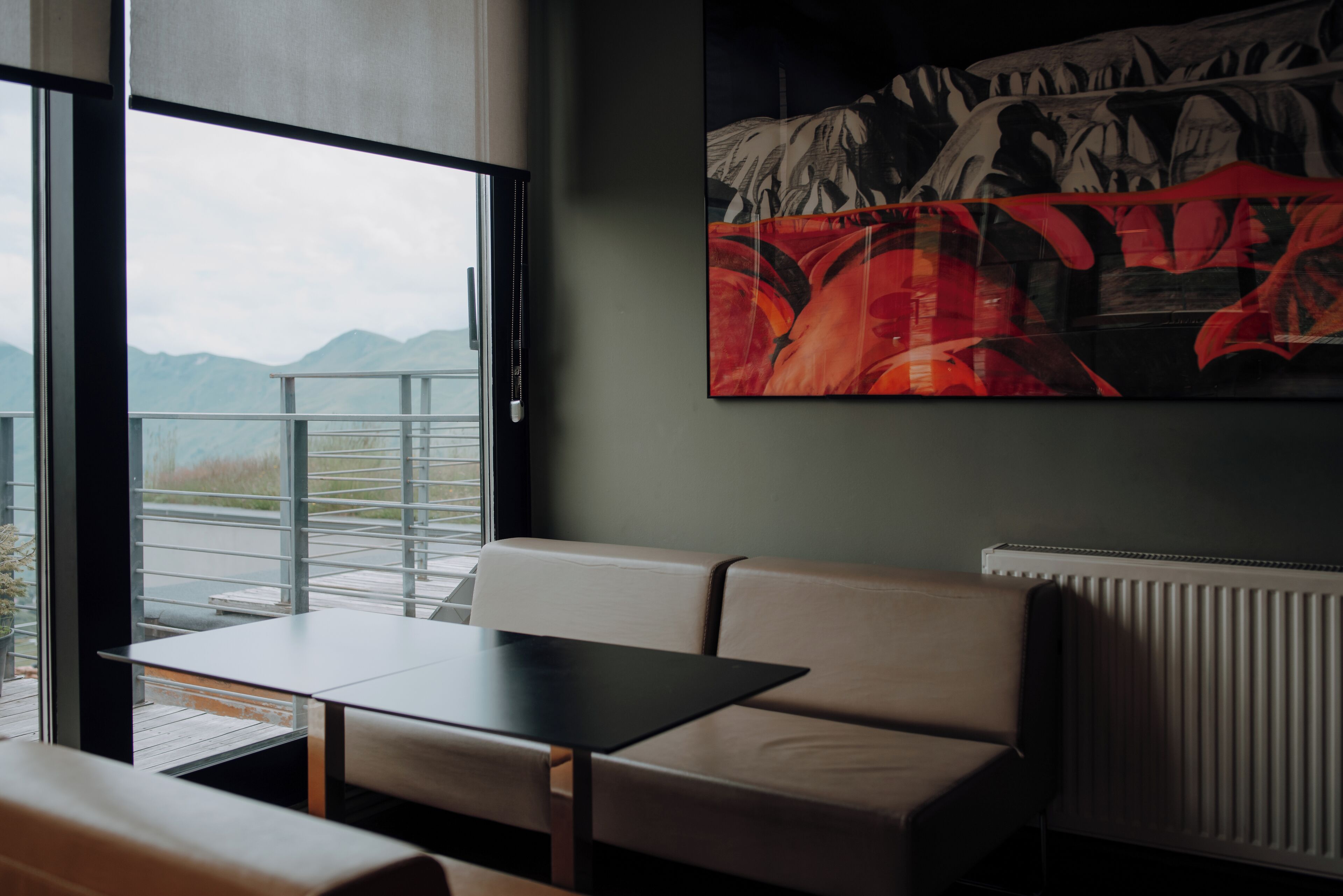 A modern interior with a sofa, a table, and a large window offering a mountain view.