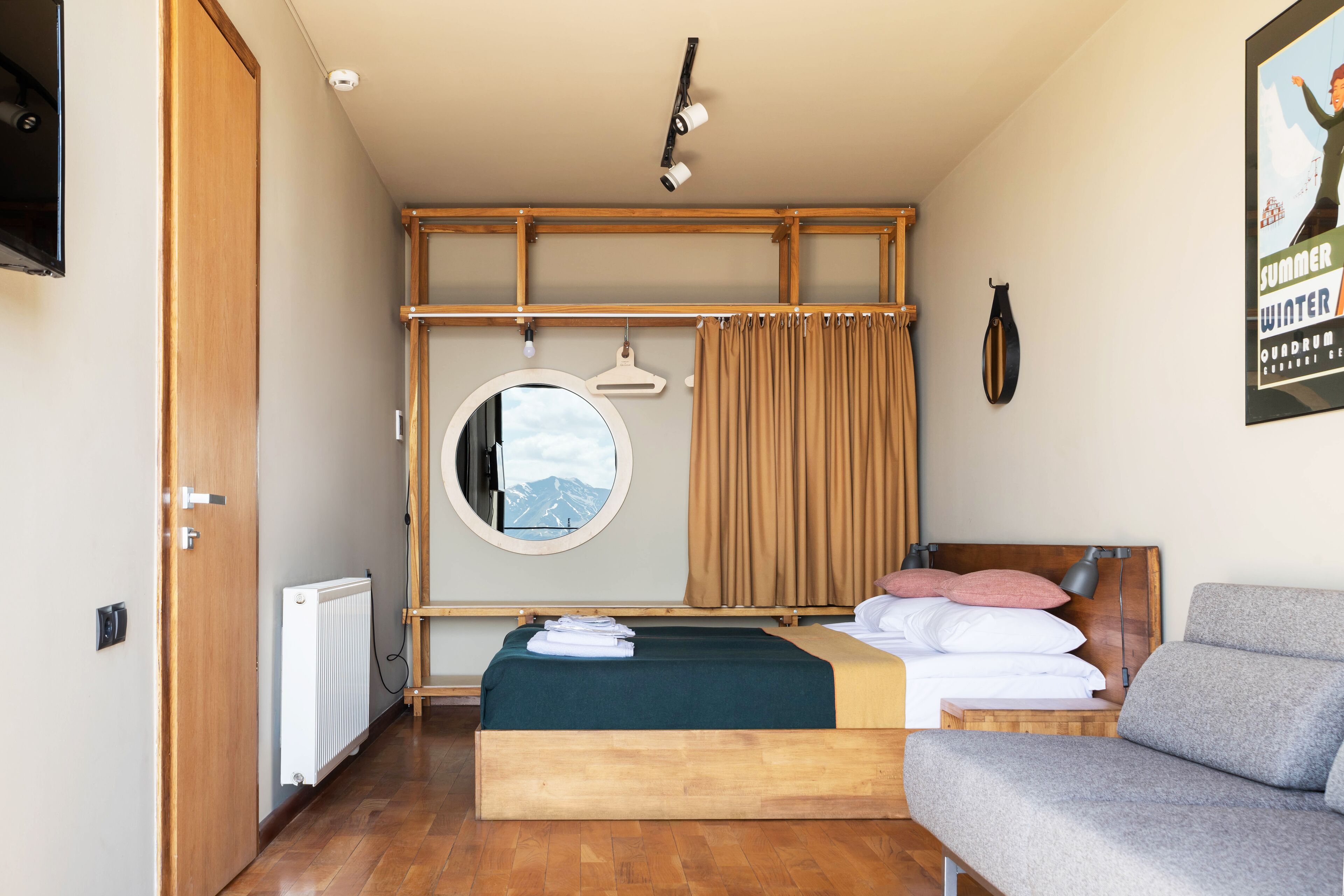 Un dormitorio con cama, sofá, espejo, radiador y un cartel en la pared.