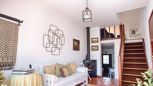 Una sala de estar con un sofá blanco, una mesita con libros, una chimenea y una escalera de madera.