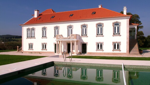 Un edificio grande y blanco con techo rojo y una piscina delantera.