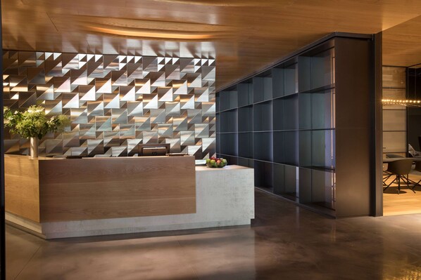 Un área de recepción con un diseño geométrico en la pared, un mostrador de madera y una zona de estar de estilo moderno.