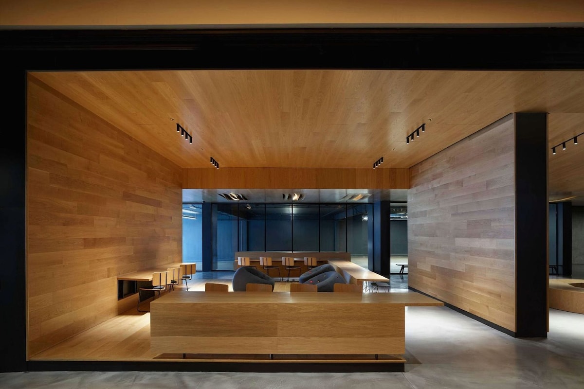 A modern interior with a central seating area, wooden walls, and a glass partition in the background.