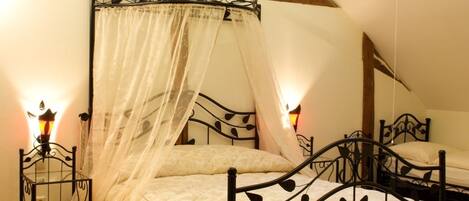 Una camera da letto con un letto a baldacchino, travi in legno e soffitto a falde.
