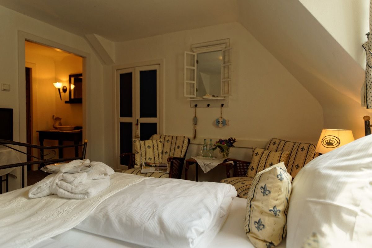 Une chambre d’hôtel avec un lit, une chaise, une table et un miroir.