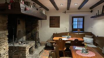 Un comedor rústico con chimenea de piedra, mesas y bancos de madera.