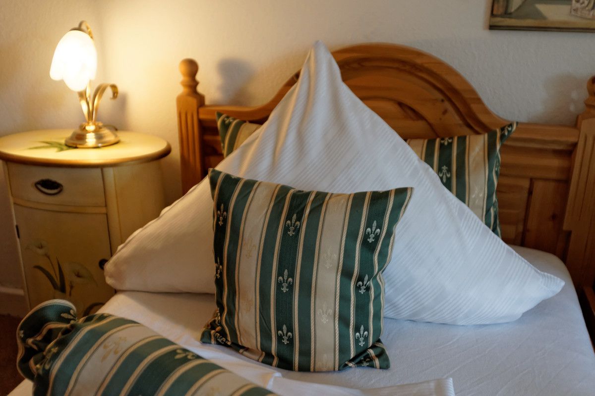 Een bed met gestreepte kussens, een bedlamp en een houten hoofdbord.