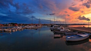 A marina with boats docked at calm water, surrounded by a calm sea and a sunset sky. - Apartments Tomislav (Bibinje)