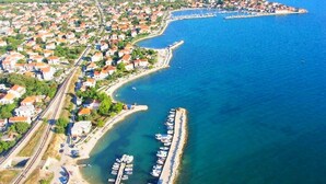An aerial view of a coastal town with a marina, residential areas, and a railway line. - Apartments Tomislav (Bibinje)