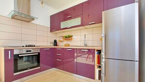 A modern kitchen with a built-in oven, a stainless steel refrigerator, and a wooden countertop. - Apartments Tomislav (Bibinje)