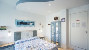 A hotel room with a bed, a desk, a mirror, and a wardrobe. - Versomare (Polignano a Mare)