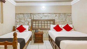 A hotel room with two beds, a stone wall, a nightstand with a phone, and a wooden headboard. - Capital O Colina Dorada (Oaxaca)