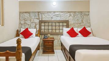 Una habitación con dos camas, pared de piedra, cabecera de madera, mesita de noche y teléfono.