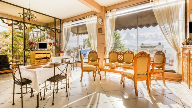 Una habitación luminosa con una mesa de comedor, sillas, un televisor y vistas a la ciudad.