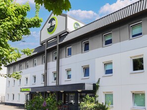 Ein Bed & Breakfast Hotel mit modernem Design, das ein markantes Logo an der Fassade, mehrere Fenster und eine gepflegte Außenansicht zeigt.